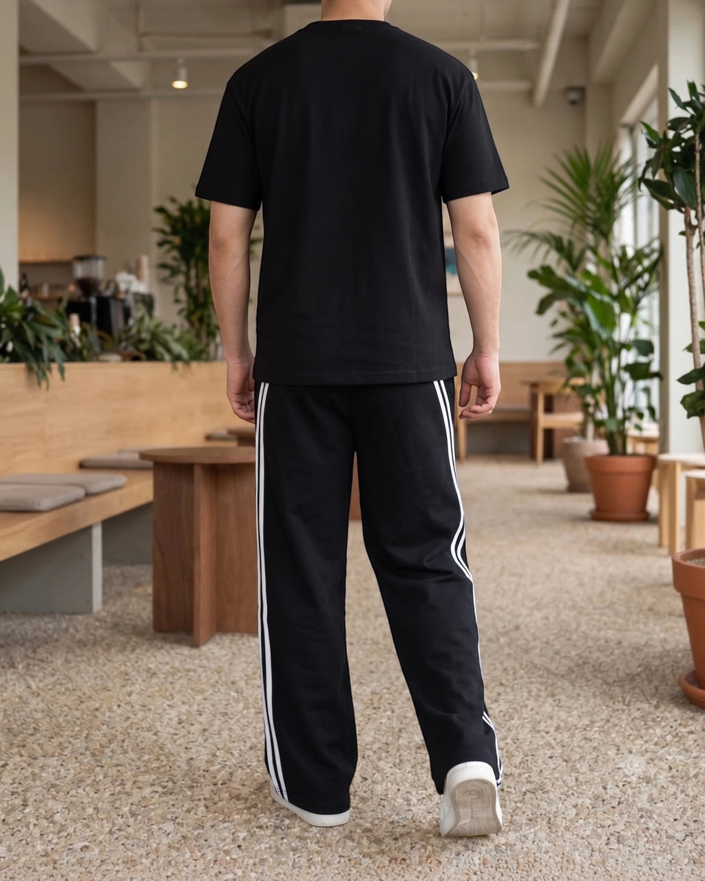 Black wide-leg sweatpants with double white side stripes, back view