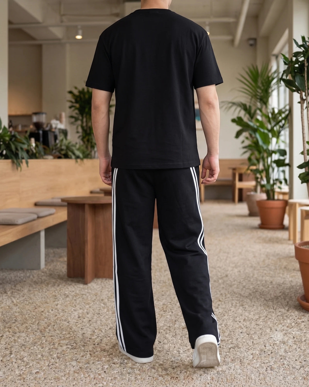 Black wide-leg sweatpants with double white side stripes, back view