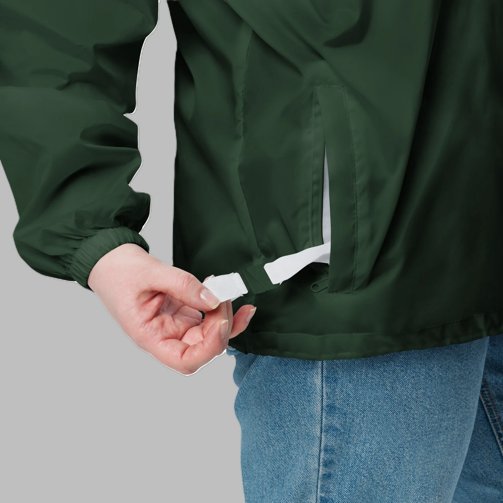 Close-up of forest green packable windbreaker jacket showing side zippered pocket and inner white carrying strap