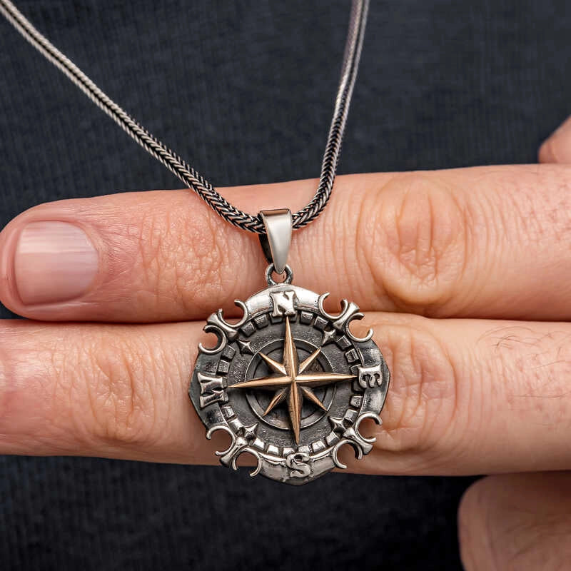 Silver nautical compass pendant held in hand showing two-tone detail