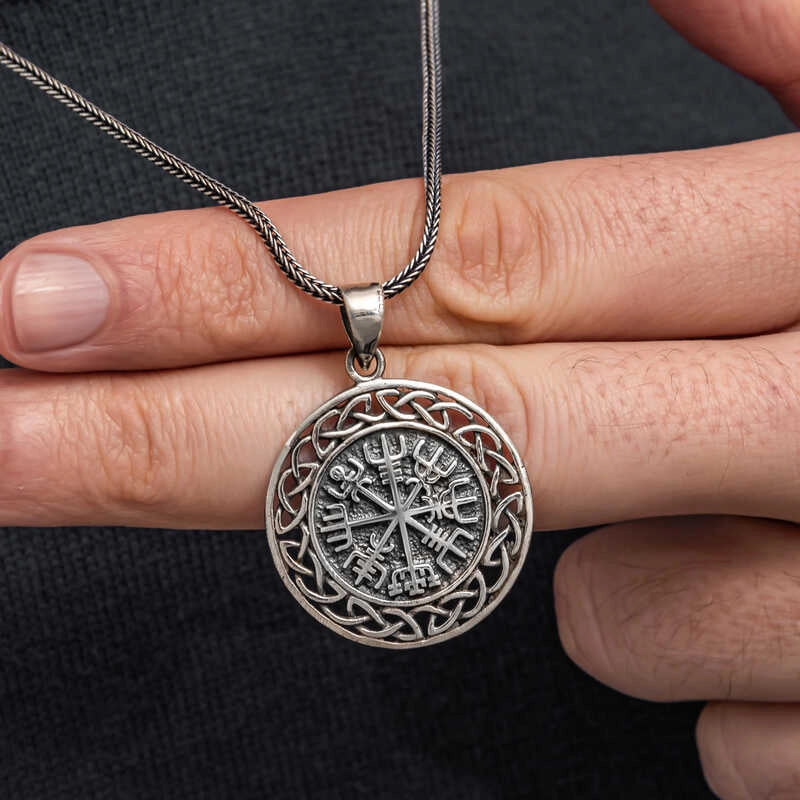 Men's oxidized silver Vegvisir pendant held in hand showing Norse rune detail
