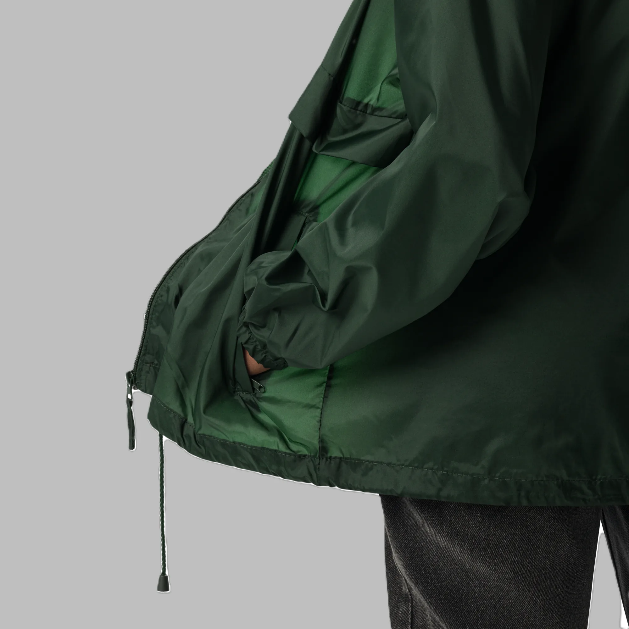 Close-up shot of lightweight dark green windbreaker jacket showing inner lining, elastic cuffs, and bottom drawstring detail