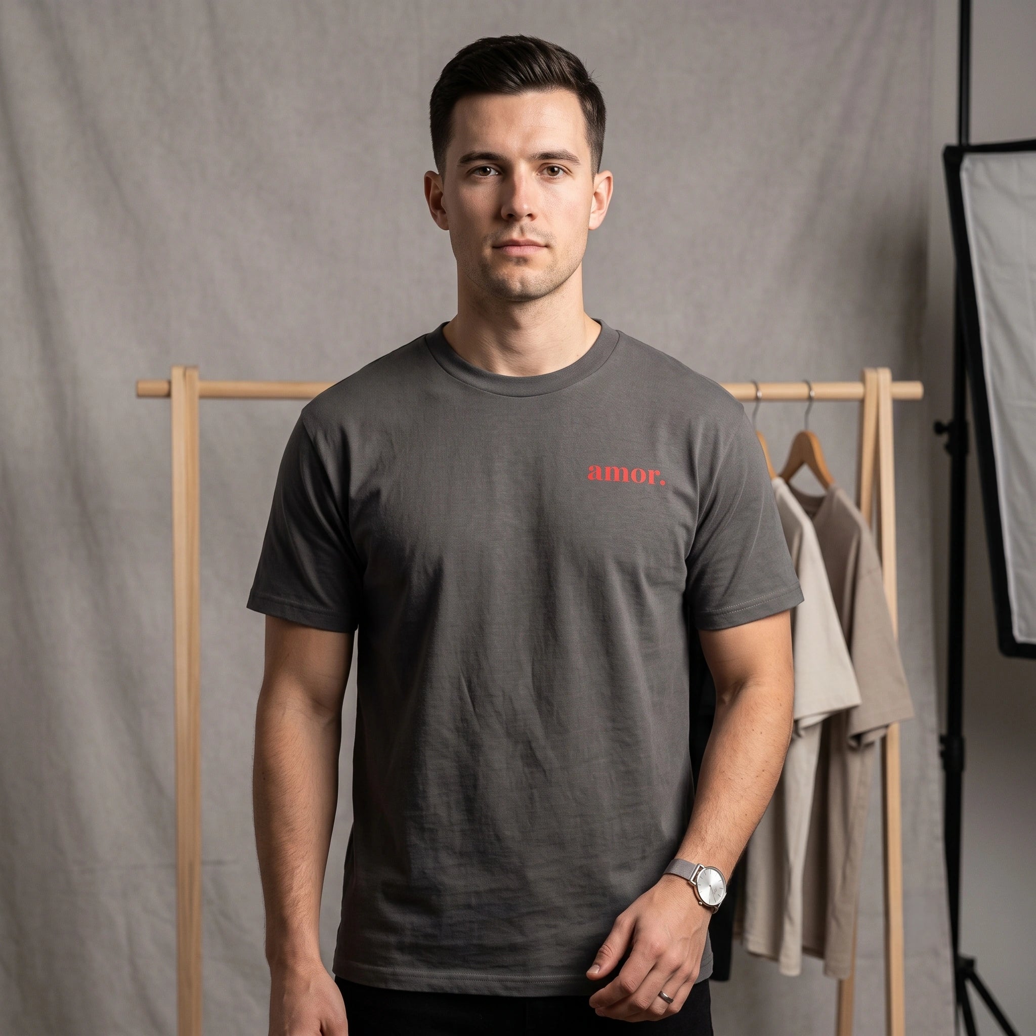 Front view of male model wearing faded black heavyweight garment-dyed t-shirt with small red amor text print on chest