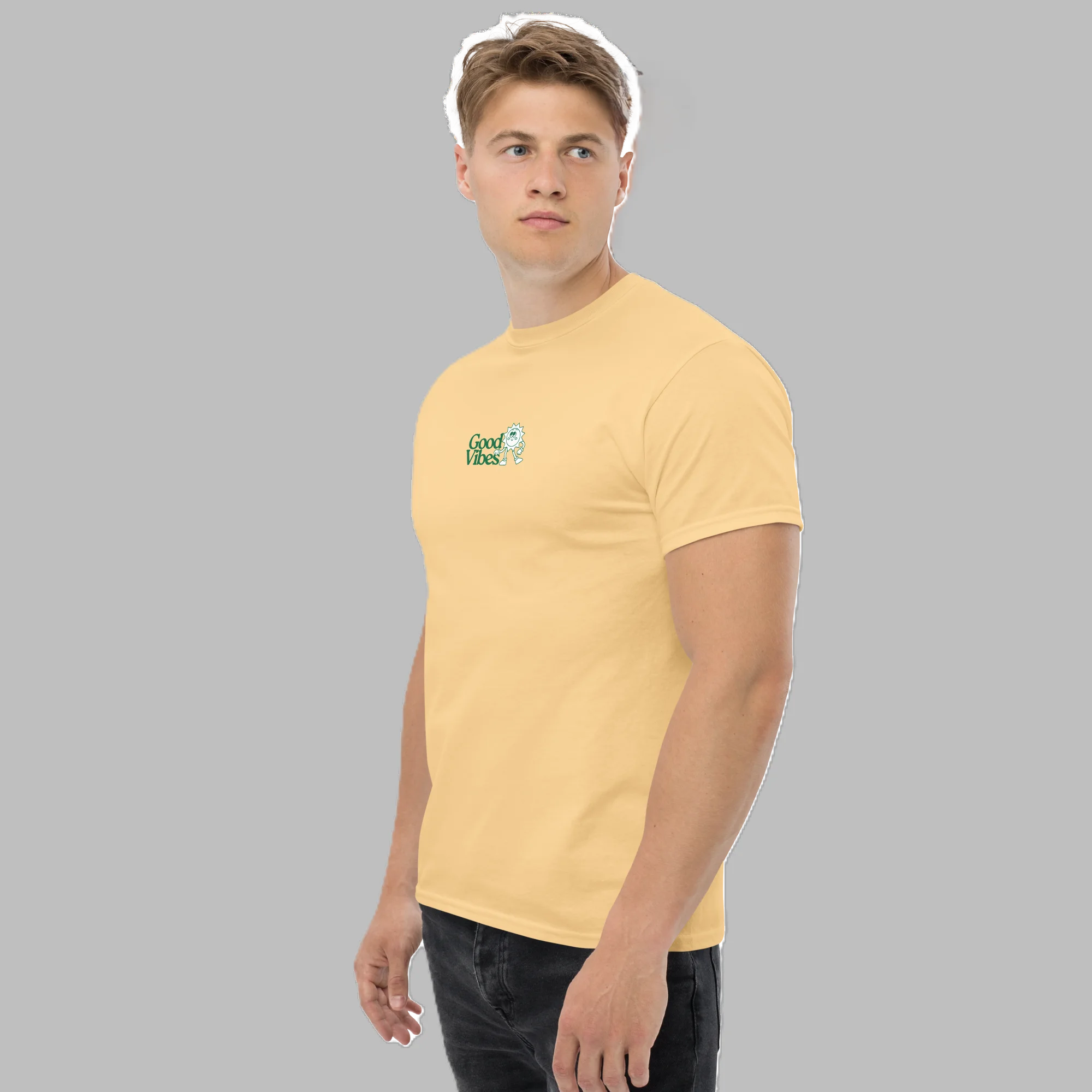 Front three-quarter view of male model wearing pastel yellow graphic t-shirt with small Good Vibes logo