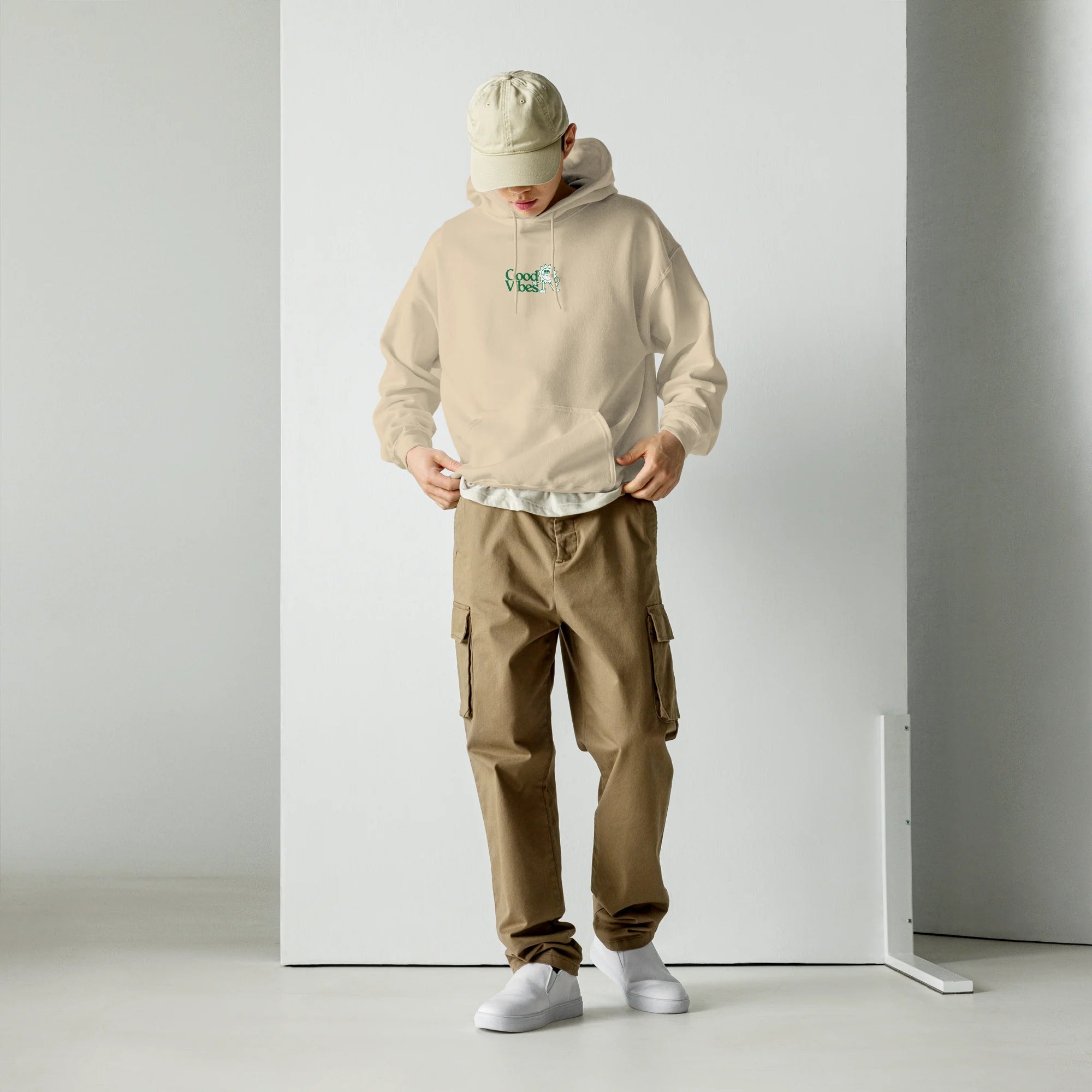 Full body shot of male model wearing sand beige Good Vibes hoodie with khaki cargo pants streetwear outfit