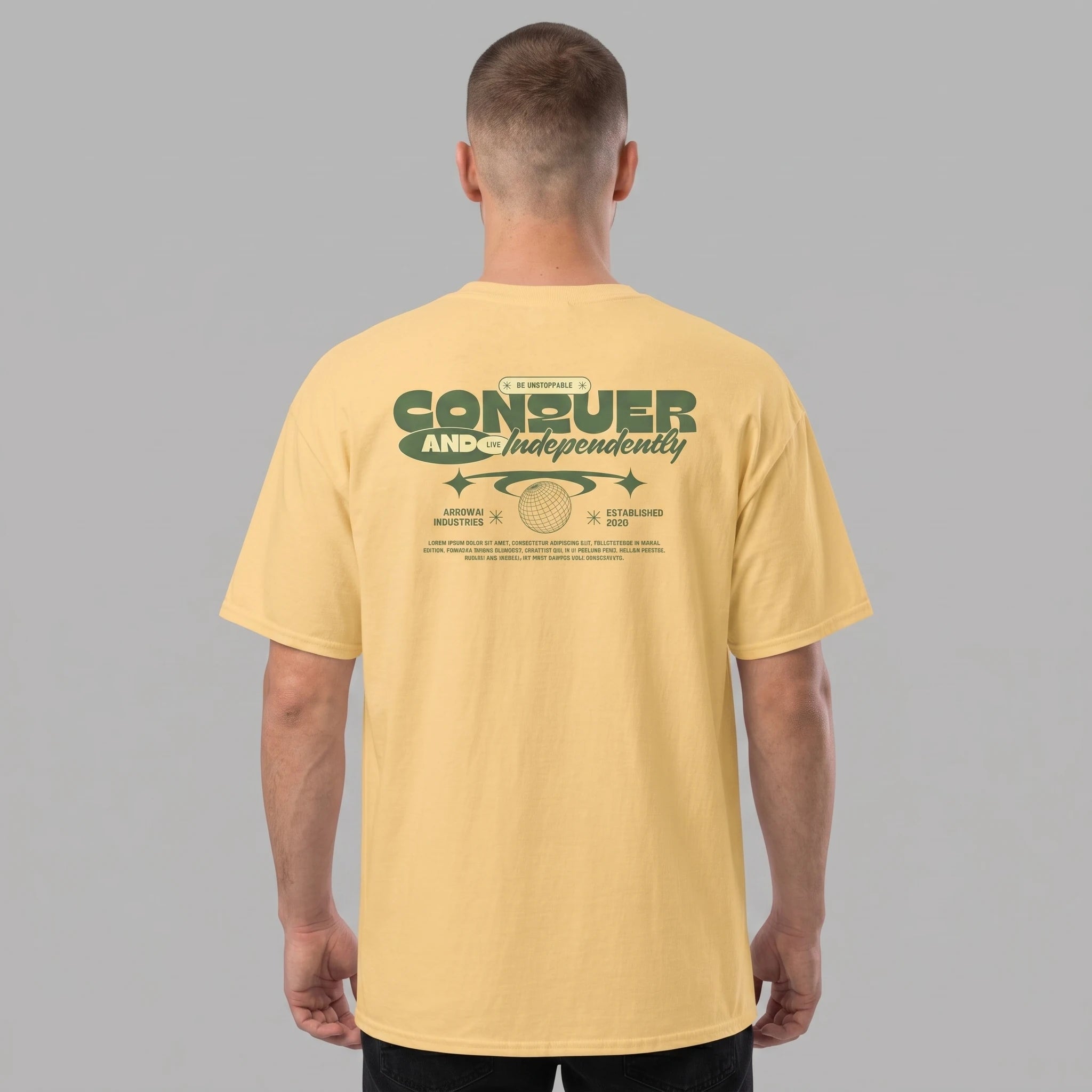 Back view of a male model wearing a pastel yellow streetwear t-shirt featuring a green Conquer graphic print on the back.