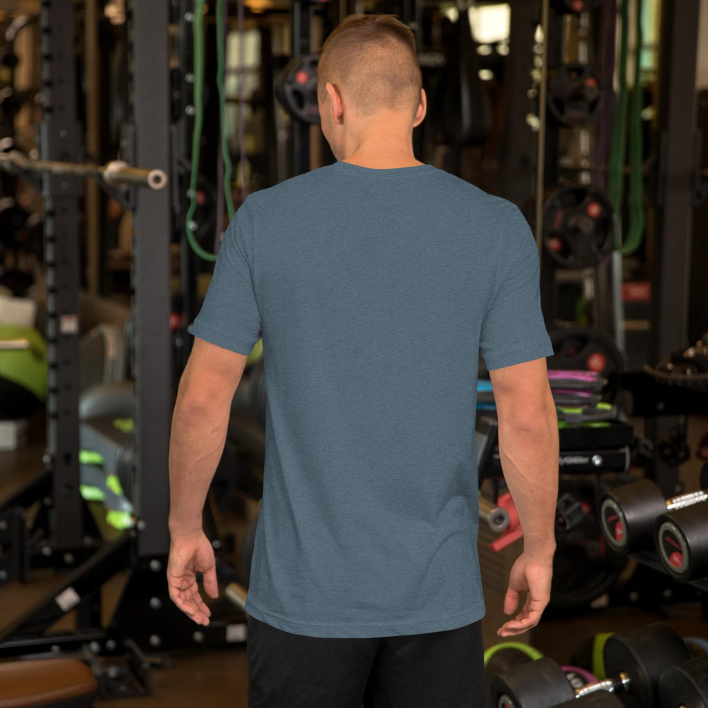 Rear view of a male model in a gym wearing a heather blue men's Summerween t-shirt, demonstrating the back fit and fabric drape of the spooky summer graphic tee.