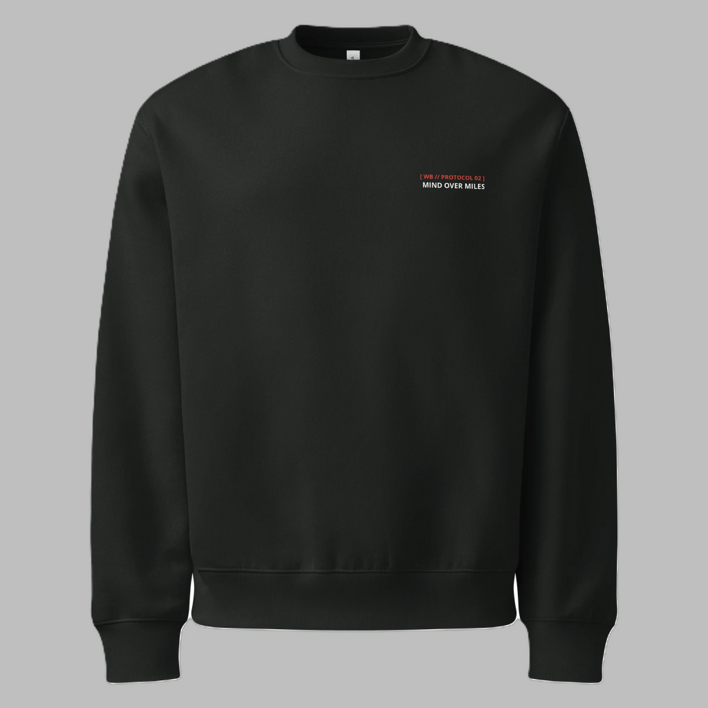 Front flat lay view of a black crewneck sweatshirt against a grey background, featuring minimalist text on the left chest with '[ WB // PROTOCOL 02 ]' in red and 'MIND OVER MILES' in white.