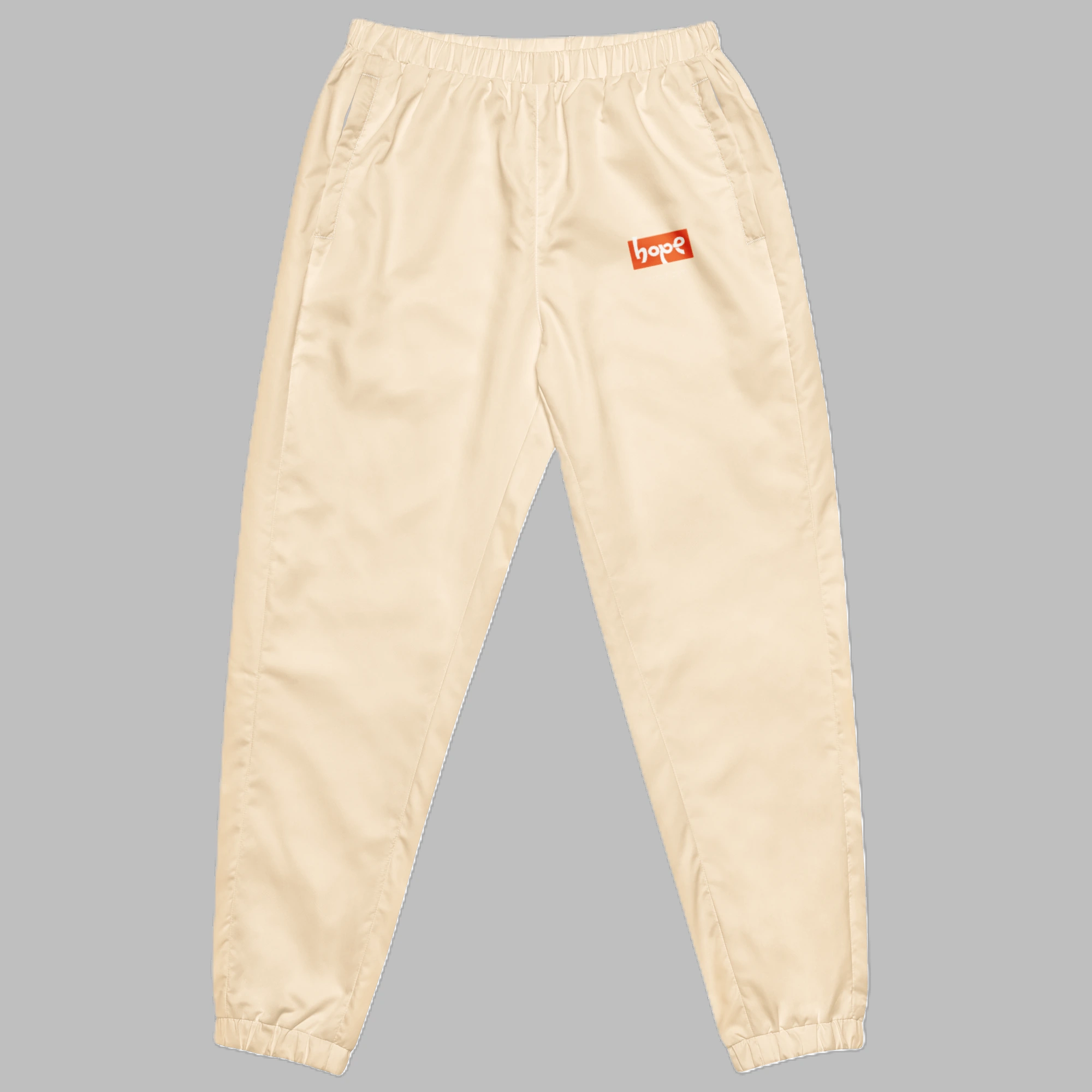 Sand beige unisex streetwear track pants with orange Hope logo and elastic cuffs front view