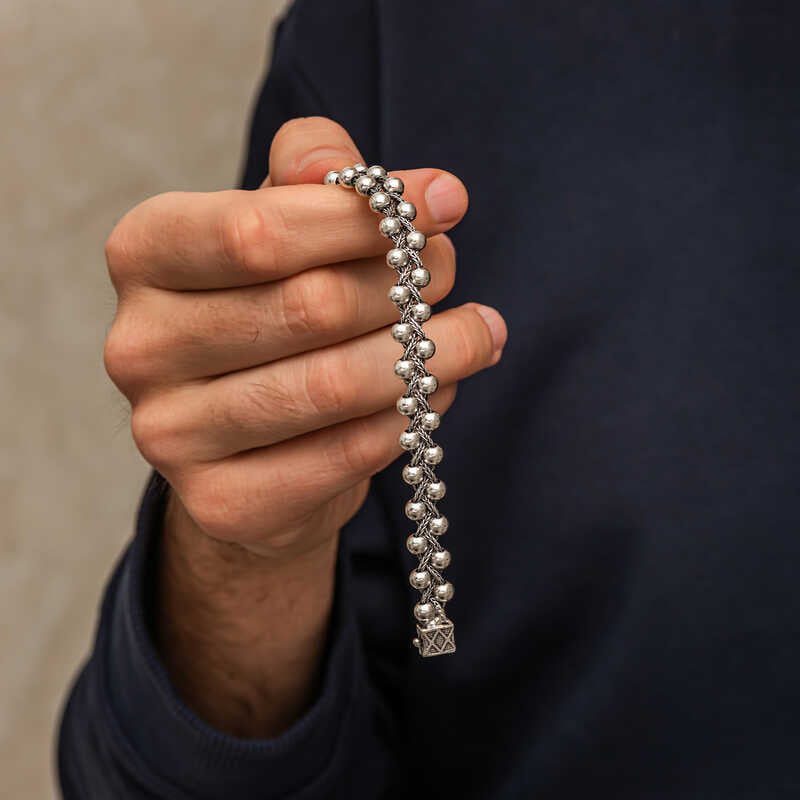 Men's sterling silver bead bracelet held in hand showing oxidized double row ball links