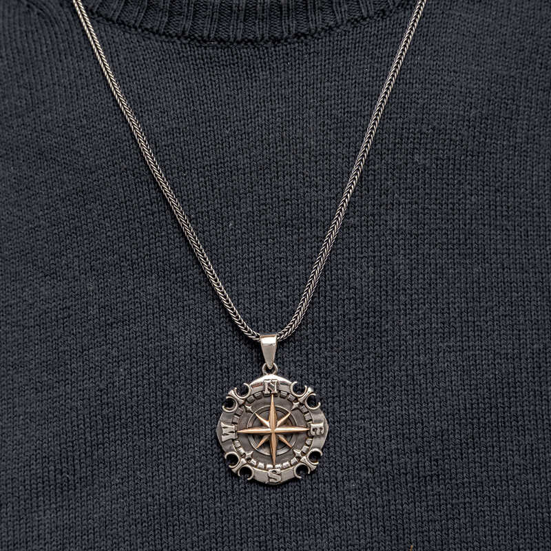 Man wearing oxidized silver compass necklace over black t-shirt