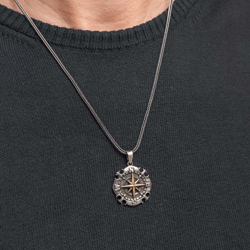 Close-up of men's silver compass necklace on chest