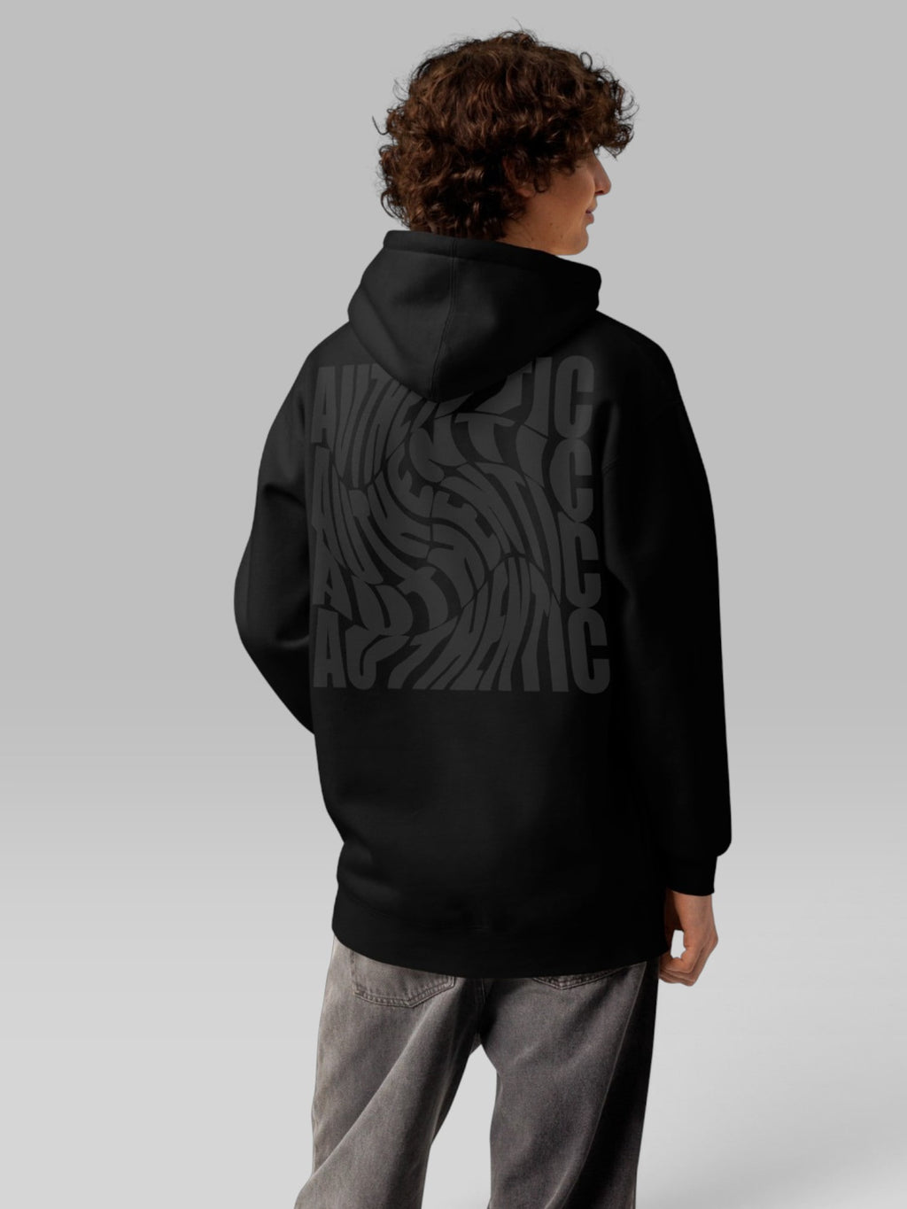 Back view of a model wearing a black oversized hoodie with a wavy graphic print
