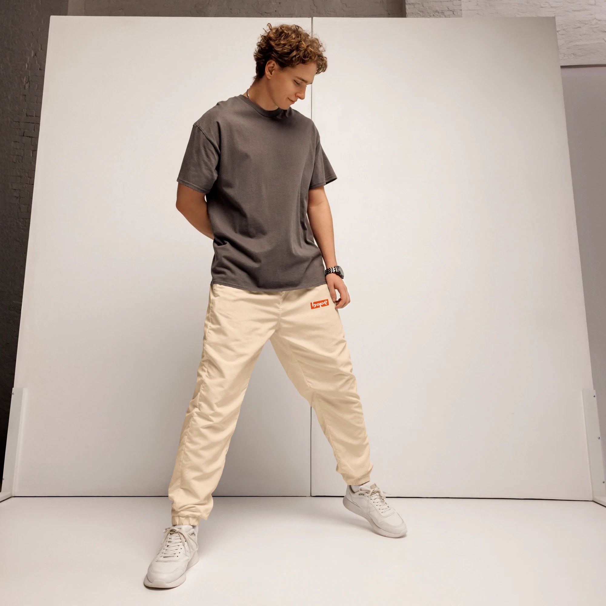 Full body shot of male model wearing sand beige unisex track pants jogger with charcoal grey t-shirt streetwear outfit