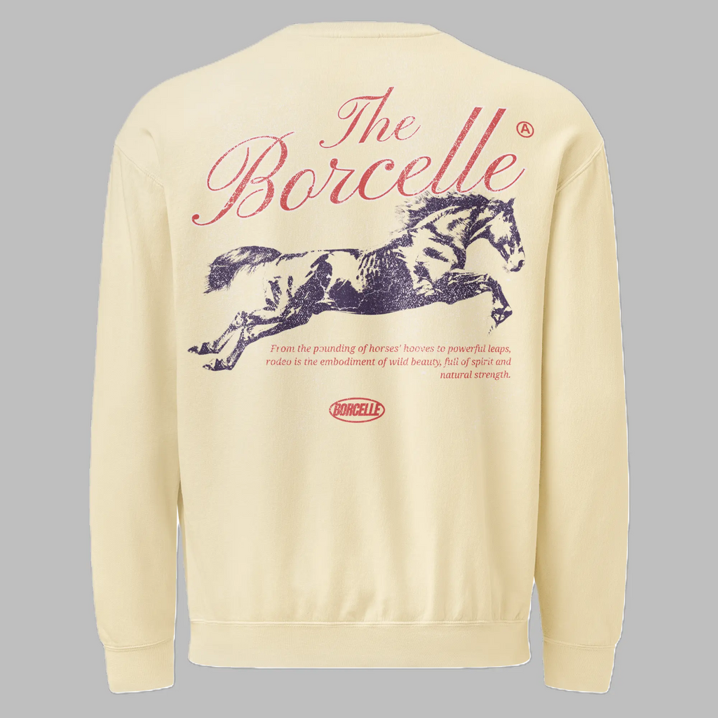 Back of an ivory crewneck sweatshirt. The top features the text The Borcelle in large, red, cursive lettering. In the center is a dark, distressed graphic of a galloping horse. Below the horse, small red text reads: From the pounding of horses' hooves to powerful leaps, rodeo is the embodiment of wild beauty, full of spirit and natural strength. A small red oval logo with the word BORCELLE is at the bottom center.