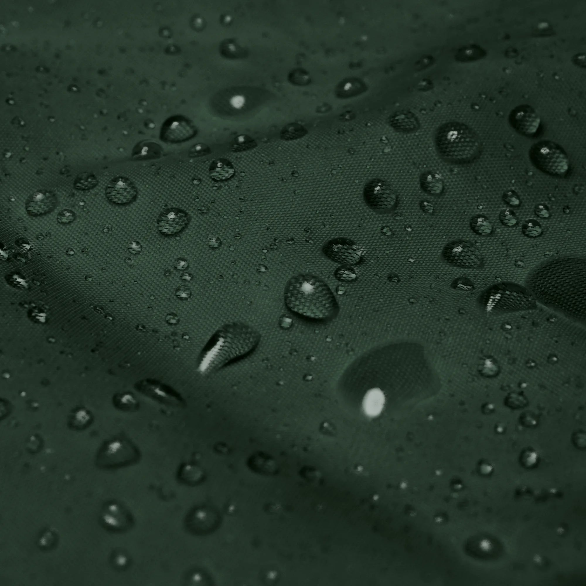 Macro close-up shot of water drops on waterproof forest green windbreaker fabric texture showcasing water-resistant feature